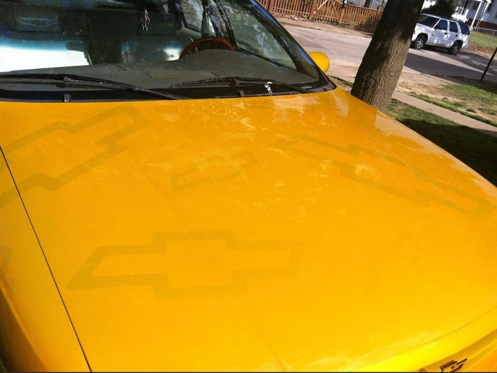 Close-up of a gold hood with Chevy bowtie ghost graphics in the paint