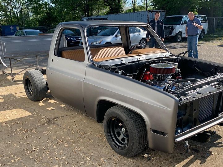 Square-body Chevy pickup finished in satin charcoal, hood up, parked outside the shop