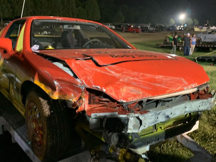 Race car on its trailer at night with the front end crushed