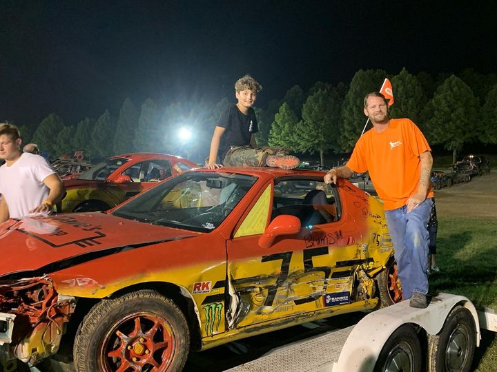 The #75 car on its trailer at night with the crew around it